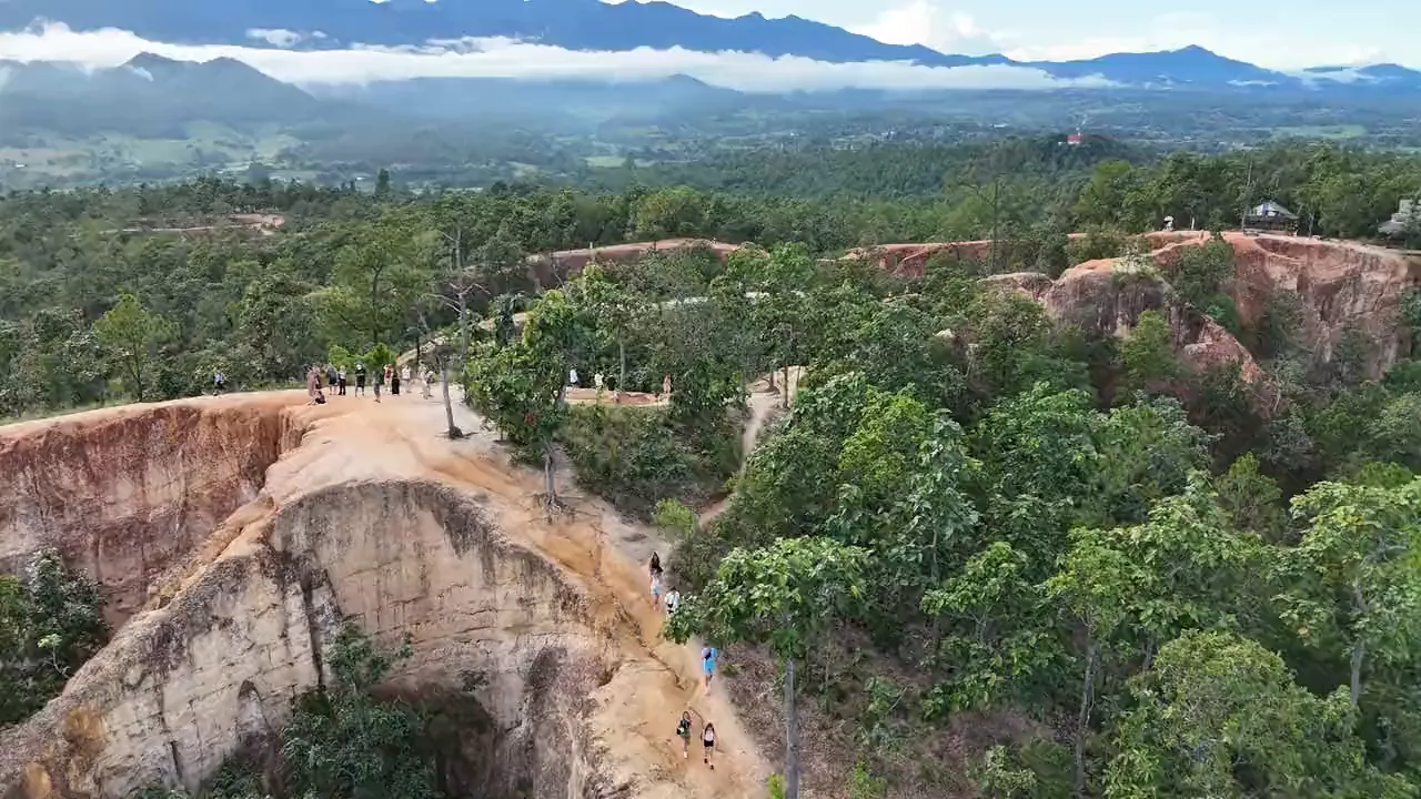 Pai Canyon from the air: walkers on the red earth ridges, with the forest, the valley and the mountains beyond