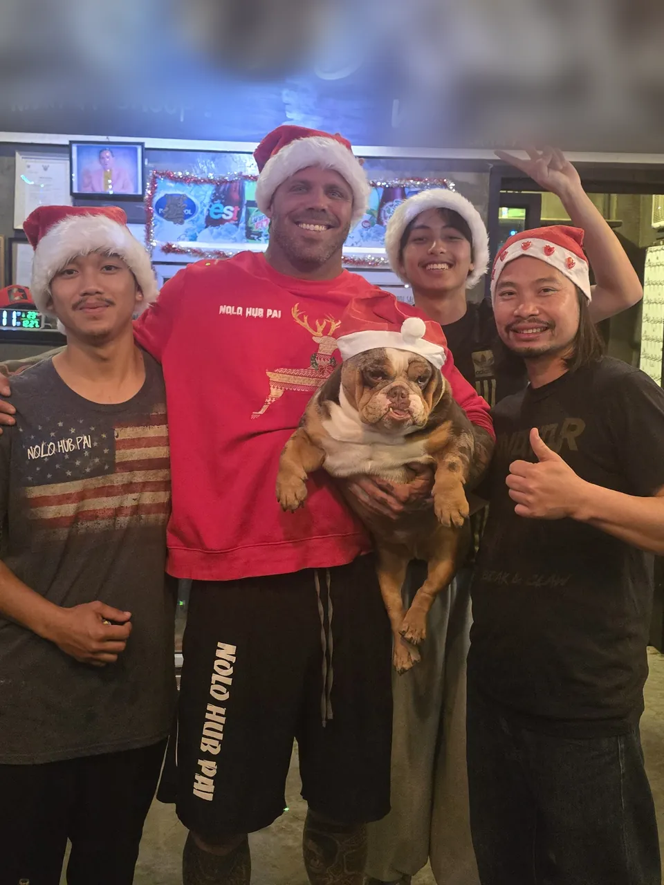 Four of the Nolo Hub Pai team in Santa hats, one holding a bulldog in a Santa hat