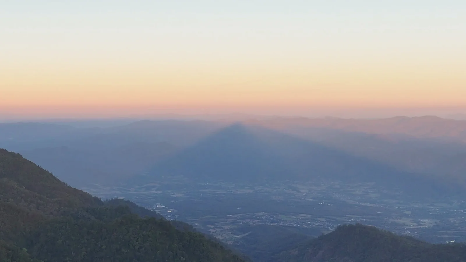 Doi Thong's triangular shadow lying across the valley in the haze at sunset