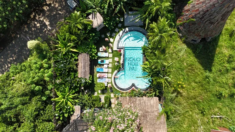 Nolo Hub’s pool from above, NOLO HUB PAI in tiles along its length, with the loungers and the garden around it