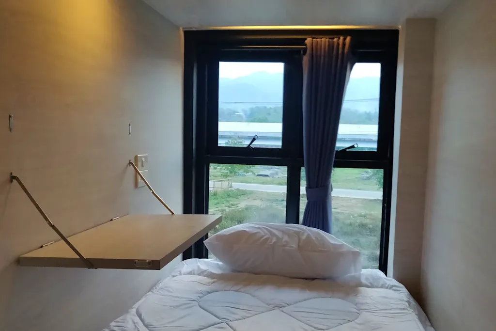 Inside a pod at Nolo Hub: the bed, the fold-down desk and a window looking out towards the mountains