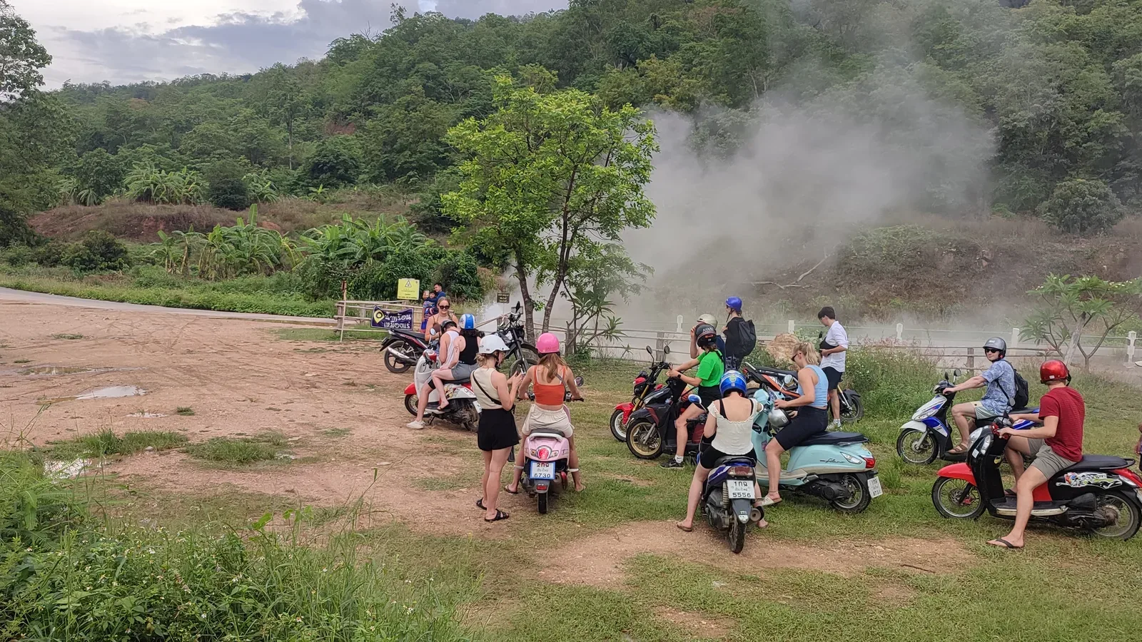 Steam rising from the well beside the road at Muang Rae, with riders stopped to look