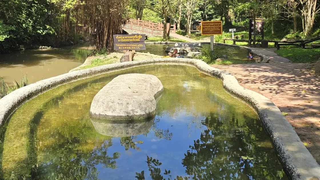 A stone-edged bathing pool at Tha Pai, with people soaking in the next pool along