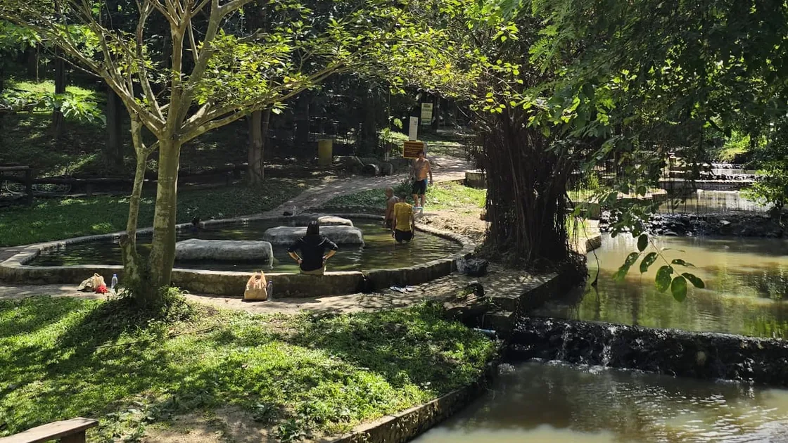Visitors in one of the bathing pools at Tha Pai, under the trees beside the stream