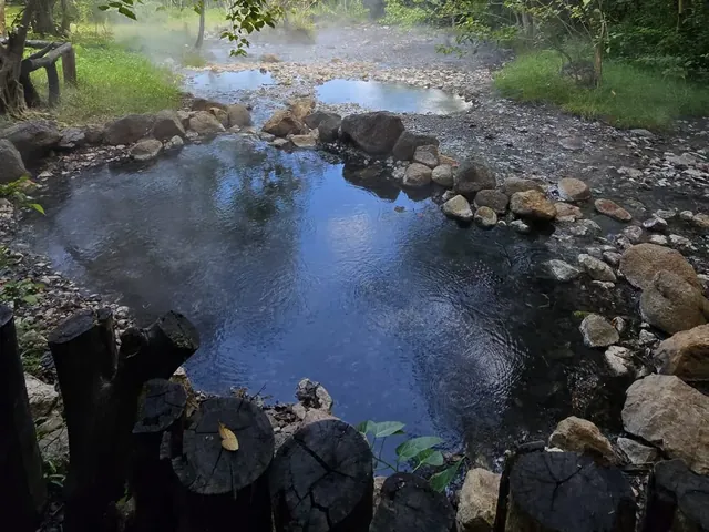 Steam rising off the fenced source pool at Tha Pai Hot Spring