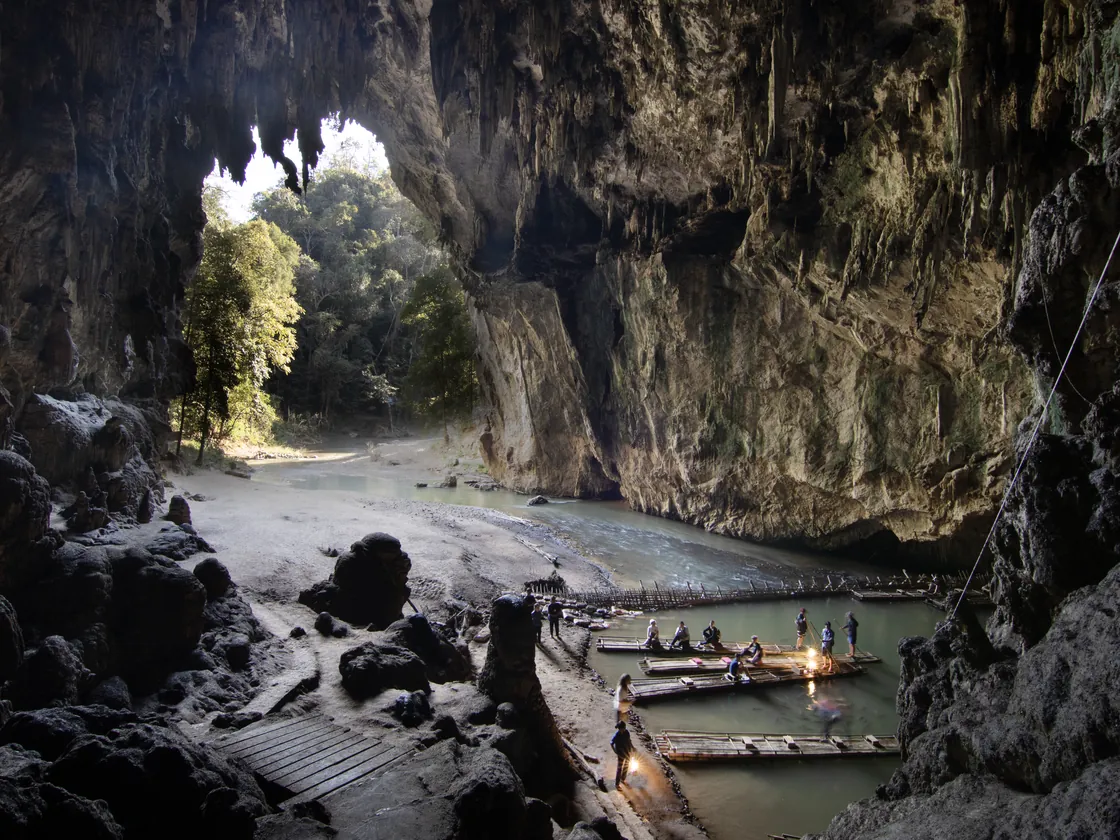 Inside Tham Lod: the river running through the cave, with bamboo rafts and the daylight at the cave mouth