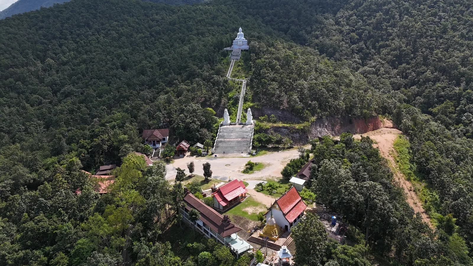The temple at the foot of the hill, with the staircase climbing through the forest to the White Buddha