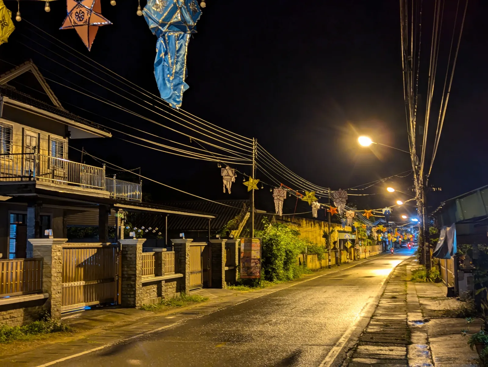 A street at night hung with Lanna lanterns and paper stars